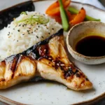 Grilled hamachi collar served with rice, vegetables, and dipping sauce.